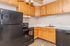 Modern kitchen featuring elegant wooden cabinetry, sleek black appliances, including a refrigerator and stove, and a spacious countertop.