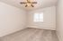 Bright, freshly painted bedroom with plush carpet, featuring a ceiling fan and a window with vertical blinds, ideal for a cozy living space.