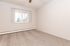 Bright and airy bedroom with plush carpeting and natural light through wide window blinds.
