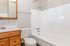 Bright and modern bathroom featuring a sleek white bathtub, polished countertop, and elegant wood cabinetry.