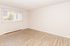 Spacious, bright room with elegant wood flooring and a large window, perfect for a cozy living area.