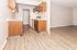 Bright and inviting kitchen with modern appliances, warm wood cabinetry, and sleek laminate flooring leading to an open living area.