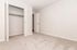 Spacious bedroom with plush carpet and open closet, perfect for cozy and modern living.