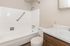Spacious bathroom featuring a sleek white bathtub, modern countertop, and elegant wood cabinetry, designed for comfort and style.