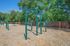 Inviting outdoor fitness area with green workout equipment set against a backdrop of lush trees, perfect for an energizing exercise experience.