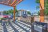 Charming apartment complex with a vibrant outdoor picnic area under a wooden pergola, featuring a stylish stone grill station and surrounded by lush trees and mountain views.
