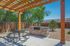 Inviting outdoor patio with pergola, durable stone grill, and black metal picnic table, ideal for entertaining and relaxation.