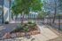 Charming apartment exterior with vibrant landscaped garden and secure wrought-iron fencing, offering a welcoming and serene atmosphere.
