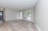 Bright and airy living room with plush carpet, modern neutral walls, and large windows offering a view of lush greenery.