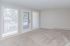Bright and inviting room with large windows, fresh carpet, and a modern neutral palette, perfect for cozy living.