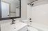 Bright and modern bathroom featuring sleek black fixtures, a large mirror, and a pristine bathtub.