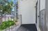 Charming apartment balcony offering a peaceful view of lush greenery and a modern exterior, perfect for relaxation.