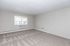 Spacious and bright carpeted room with large window, offering a cozy and inviting atmosphere.