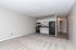 Bright open-concept living space with modern kitchen featuring sleek appliances, chic cabinetry, and plush carpet flooring in a cozy apartment.