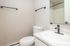 Modern bathroom with sleek fixtures, featuring a stylish granite countertop, elegant mirror, and efficient layout.