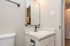 Modern bathroom corner featuring a sleek granite countertop, elegant faucet, and ambient lighting above the mirror.