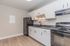 Modern kitchen with sleek black appliances, elegant white cabinetry, and sophisticated wood flooring.