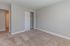 Inviting bedroom featuring plush carpet, soft gray walls, and a convenient open closet design.