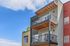 Contemporary apartment facade featuring spacious private balconies with stylish railings, set against a vibrant blue sky.