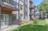 Modern apartment building with private balconies overlooking a lush green landscape, offering serene outdoor seating areas.