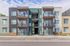 Modern apartment building featuring stylish balconies and a sleek exterior against a vibrant blue sky.