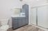 Elegant bathroom with modern gray cabinetry, a sleek white countertop, and a spacious glass-enclosed shower.