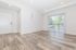 Bright, contemporary living area with sleek wooden floors and large sliding glass doors opening to a scenic balcony view.