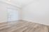 Bright, modern living space with sleek wood flooring and large window with vertical blinds, perfect for natural light.