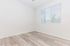 Bright and airy room with elegant light wood flooring and ample natural light from large window blinds.