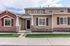 Charming townhouse exterior with a stylish blend of stone and wood accents, inviting front entrance, and manicured lawn.