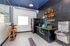 Modern kitchenette with sleek black cabinetry, granite countertops, and a vibrant blue accent. Features include a stainless steel fridge, microwave, and a cozy breakfast nook with bar stools. Stylish hexagonal tile backsplash adds elegance.