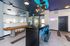 Modern communal lounge with chic seating, industrial lighting, and a shuffleboard for entertainment, featuring a mountain-themed neon sign.