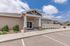 Inviting apartment complex entrance with stone accents and a neatly landscaped walkway under a bright, clear blue sky.
