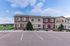 Charming two-story duplex with colorful facade, surrounded by lush greenery and open skies.