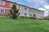 Vibrant multi-level townhomes with colorful exteriors set against a lush green lawn and clear blue sky.