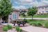 Charming suburban home featuring a cozy patio with picnic table, lush green lawn, and beautiful landscape under a vibrant blue sky.