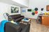 Modern apartment living room with sleek leather sofas, chic wall art, and a stylish kitchen bar with stools, perfect for entertaining.