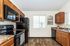 Modern kitchen with sleek black appliances, warm wooden cabinetry, and inviting natural light through large windows.