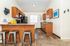 Charming kitchen with modern wooden cabinets, sleek countertops, and stylish bar stools, offering a cozy and inviting atmosphere.