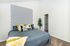 Chic bedroom with a stylish geometric accent wall, cozy gray and yellow bedding, and a walk-in closet.