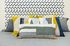 Vibrant bedroom decor with geometric-patterned accent wall and colorful, textured cushions, offering a modern and cozy vibe.