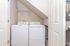 Bright and efficient laundry nook featuring modern washer and dryer set under sleek shelving.