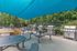 Modern outdoor barbecue area with shaded seating, contemporary grills, and lush greenery, perfect for social gatherings.