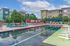 Vibrant apartment community with a luxurious outdoor pool area, featuring colorful sun loungers, stylish seating, and modern landscaping under a clear blue sky.