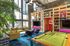 Chic lounge area featuring vibrant decor, a cozy sectional sofa, and a pool table for entertainment under high ceilings with expansive windows.