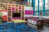 Vibrant apartment community room featuring a modern pool table, chic bar area with purple stools, and a colorful entertainment wall with a large TV.
