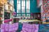 Vibrant modern living space with colorful accents, high ceilings, stylish furniture, and a sleek kitchen area.