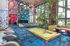 Vibrant lounge with colorful wall art, modern lighting, and a pool table, featuring lush indoor plants and cozy seating.