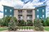 Contemporary apartment building with vibrant blue siding, green landscaping, and spacious balconies.