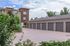 Charming apartment complex with multiple garages and lush greenery on a sunny day.